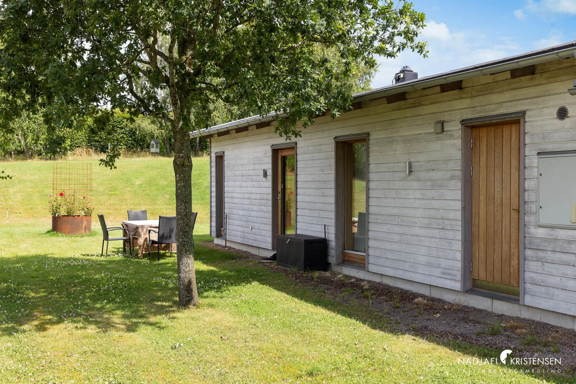 The long side of the house with seating under the oak